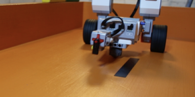 A small robot with wheels on a wooden surface